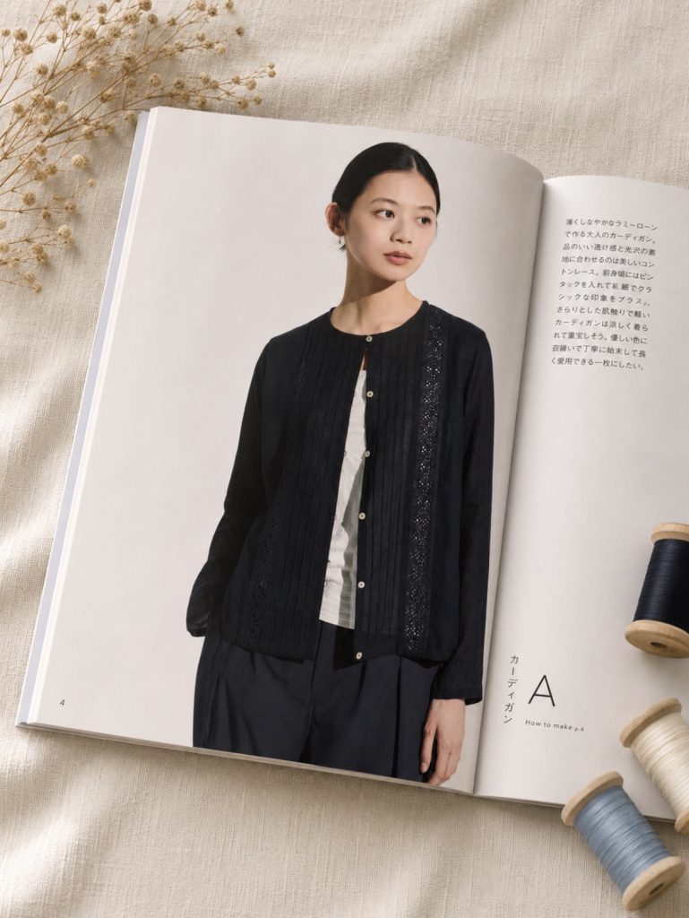a model in a fine black ramie-lawn cardigan with pintucks and cotton lace panels, worn over a white top.