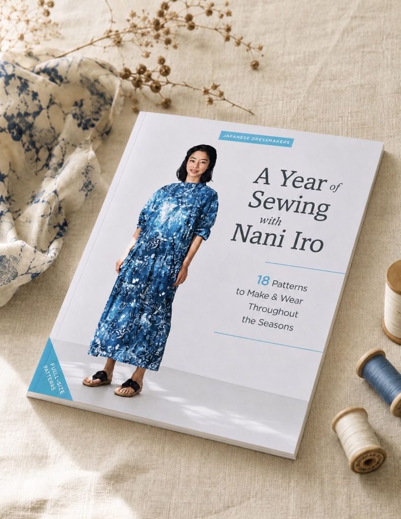 The sewing book A Year of Sewing with Nani Iro by Naomi Ito on natural linen with wooden thread spools