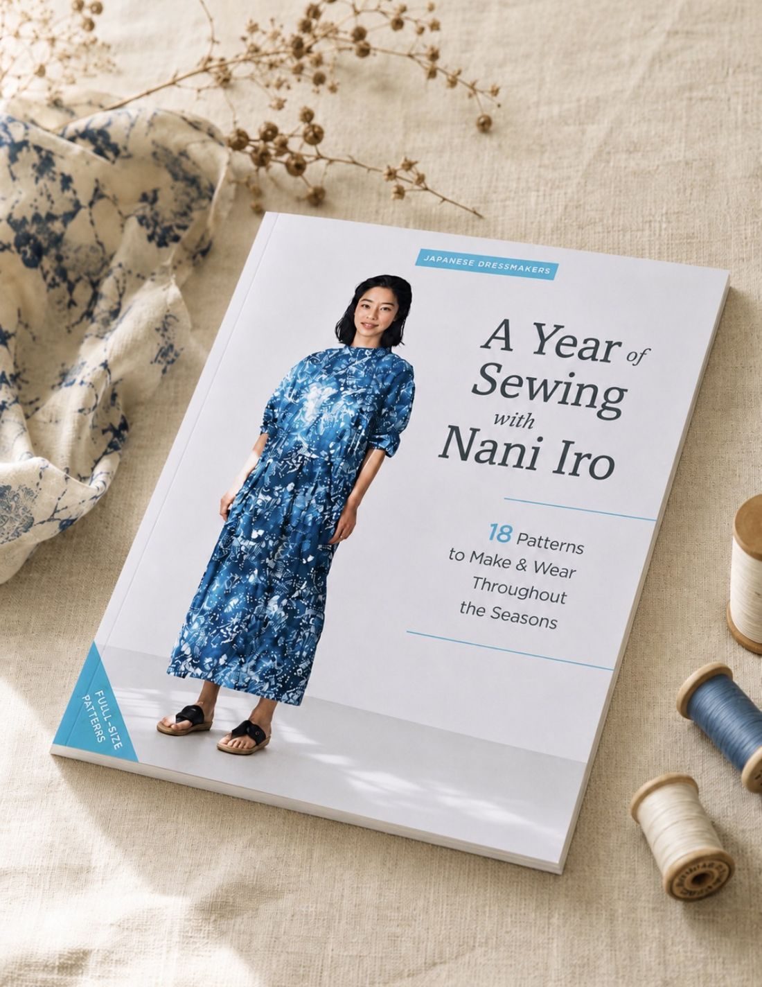 The sewing book A Year of Sewing with Nani Iro by Naomi Ito on natural linen with wooden thread spools